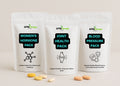 Three Alpha Omega health pack pouches on a beige background with visible pills.