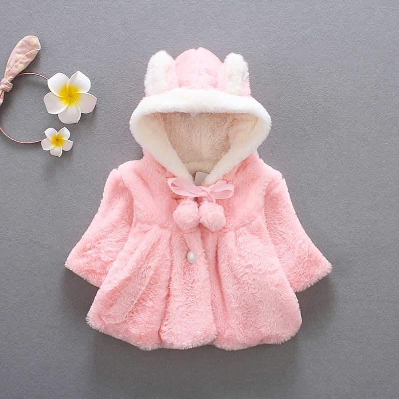 Newborn baby girl wearing a pastel pink rabbit ear fur cloak jacket with a hood
