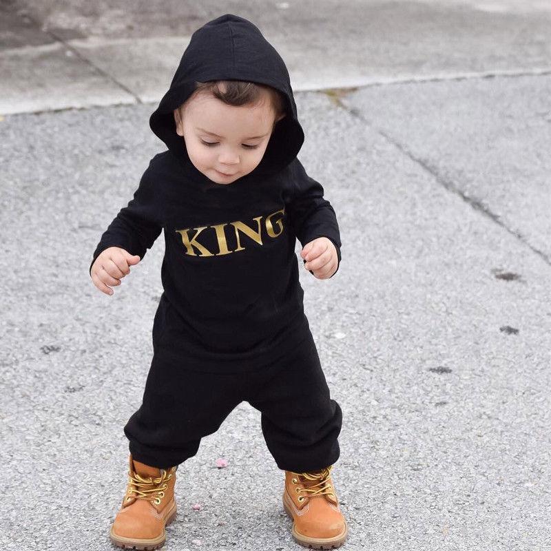 Baby boy wearing a black and yellow King print jumpsuit in a casual urban style.