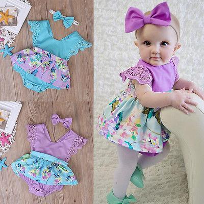 Baby girl wearing a romantic purple and teal floral print cotton romper dress with matching headband.