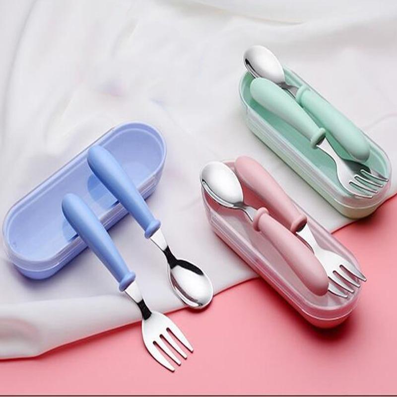 A modern toddler utensil set including a spoon and fork in blue, pink, and mint-green.
