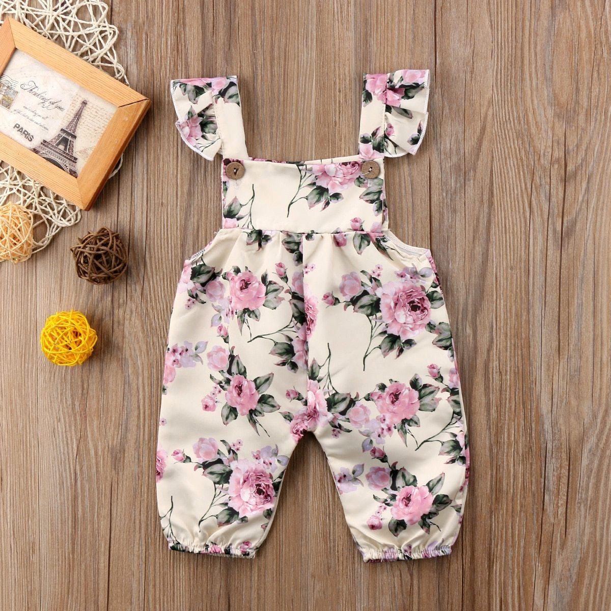 Baby girl wearing a floral patterned romper with ruffle shoulder straps