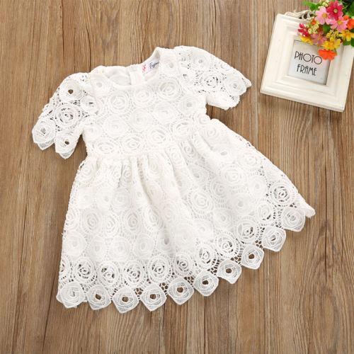 Classic white baby girl lace dress with floral pattern and short sleeves, paired with matching headband.