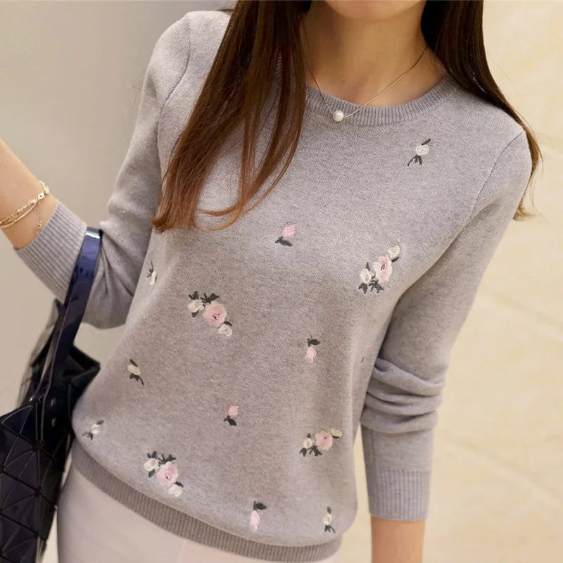 A woman wearing a soft knit pullover sweater with small floral embroidery in a casual setting.