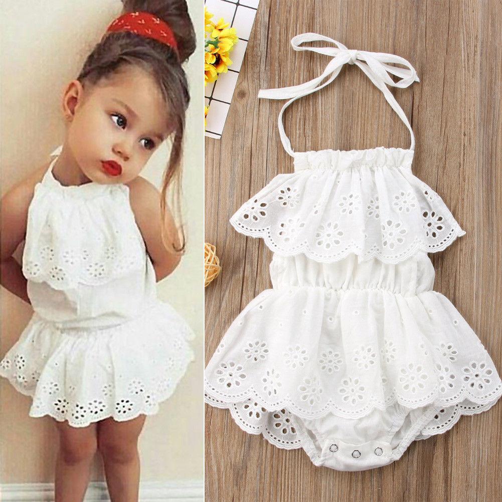Infant baby girl wearing a romantic white lace romper dress with bohemian detailing.