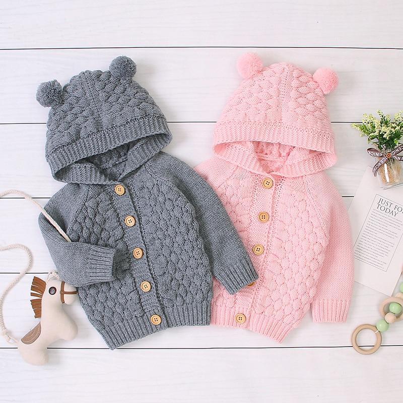 Newborn baby wearing a striped knit hooded coat with bear ears