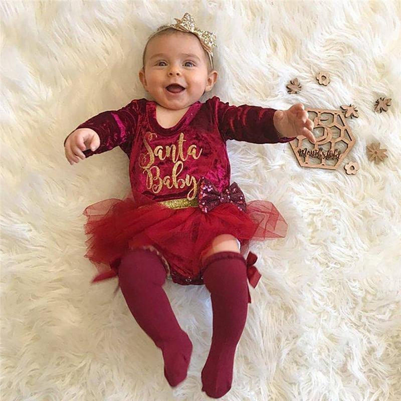 Baby girl wearing a red velvet long-sleeve Christmas dress with metallic gold lettering