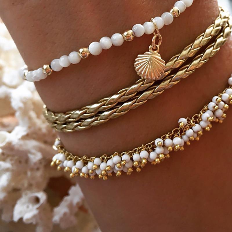 Gold tone multi-layer anklet bracelet with tassel and bead details on a woman's ankle