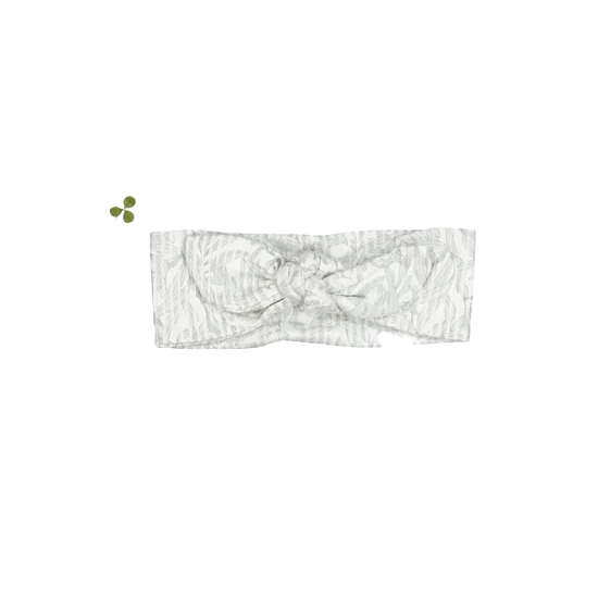 Close up of the Willa headband featuring a grey botanical leaf print on a white fabric background with a knotted bow detail.