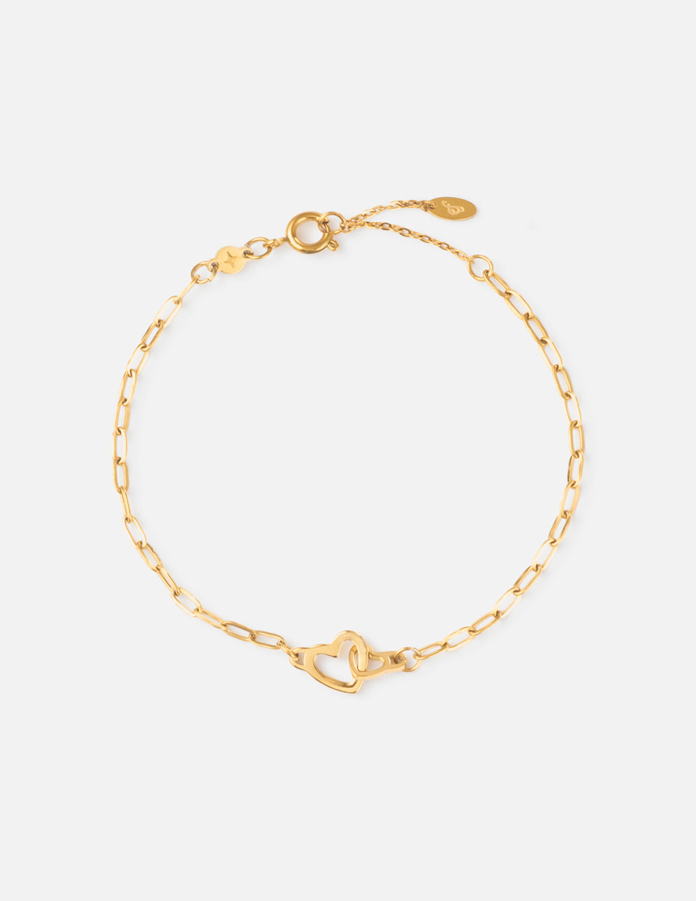 Heart charm on a gold-toned paperclip link chain bracelet on a wrist