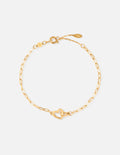 Heart charm on a gold-toned paperclip link chain bracelet on a wrist