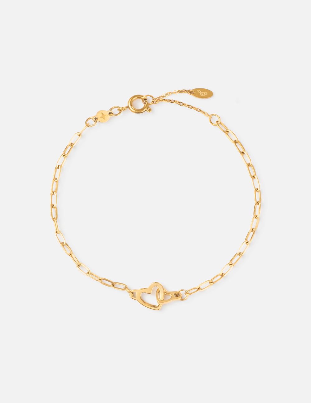 Heart charm on a gold-toned paperclip link chain bracelet on a wrist