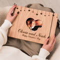 A minimalist wooden heart-themed photo album resting on a neutral tabletop, showcasing natural wood grain.