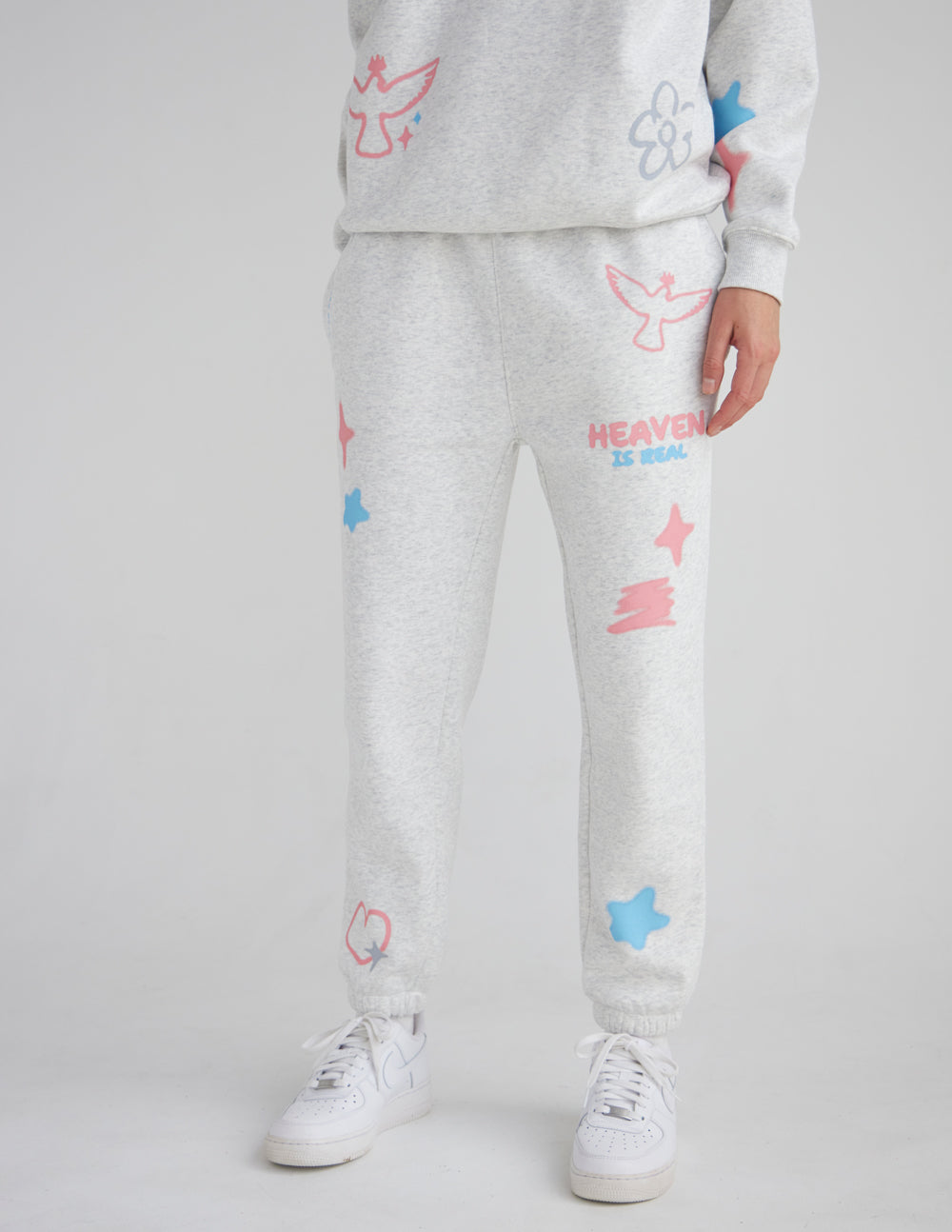 Unisex Heaven Is Real sweatpants in heather grey with pastel graphic accents on a model