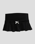 Black and white Kitty Girl micro mini skirt with pleated design, satin bow, and back rhinestone details.