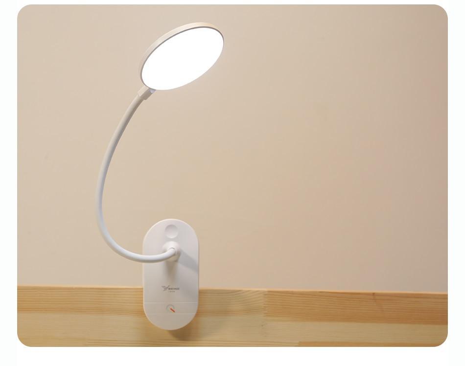 Minimalist white LED clip-on desk lamp with flexible neck on a wooden table.