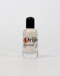 Close-up of Orijin Hibiscus Powder exfoliating cleanser being applied as a dark pink paste to a woman's cheek.
