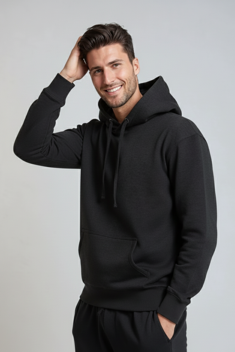 A man wearing a black midweight pullover hoodie with a drawstring hood and kangaroo pocket