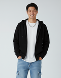 A man smiling while wearing a black heavyweight zip-up hoodie over a white t-shirt.
