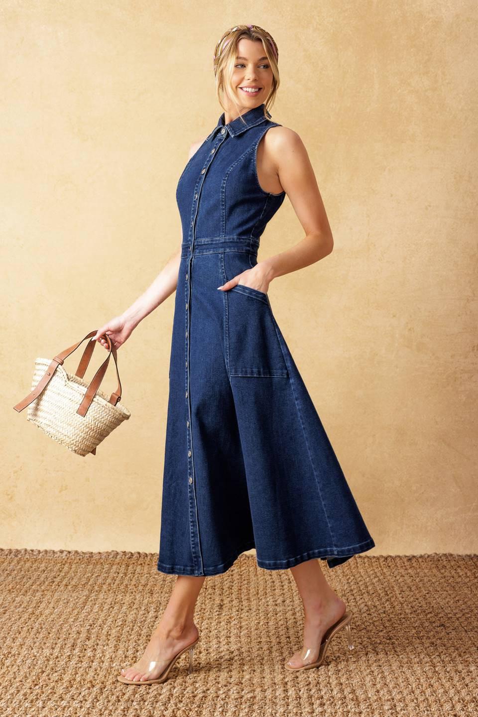A woman wearing a dark wash denim midi dress with a collar and button-down front, styled with clear heeled sandals.