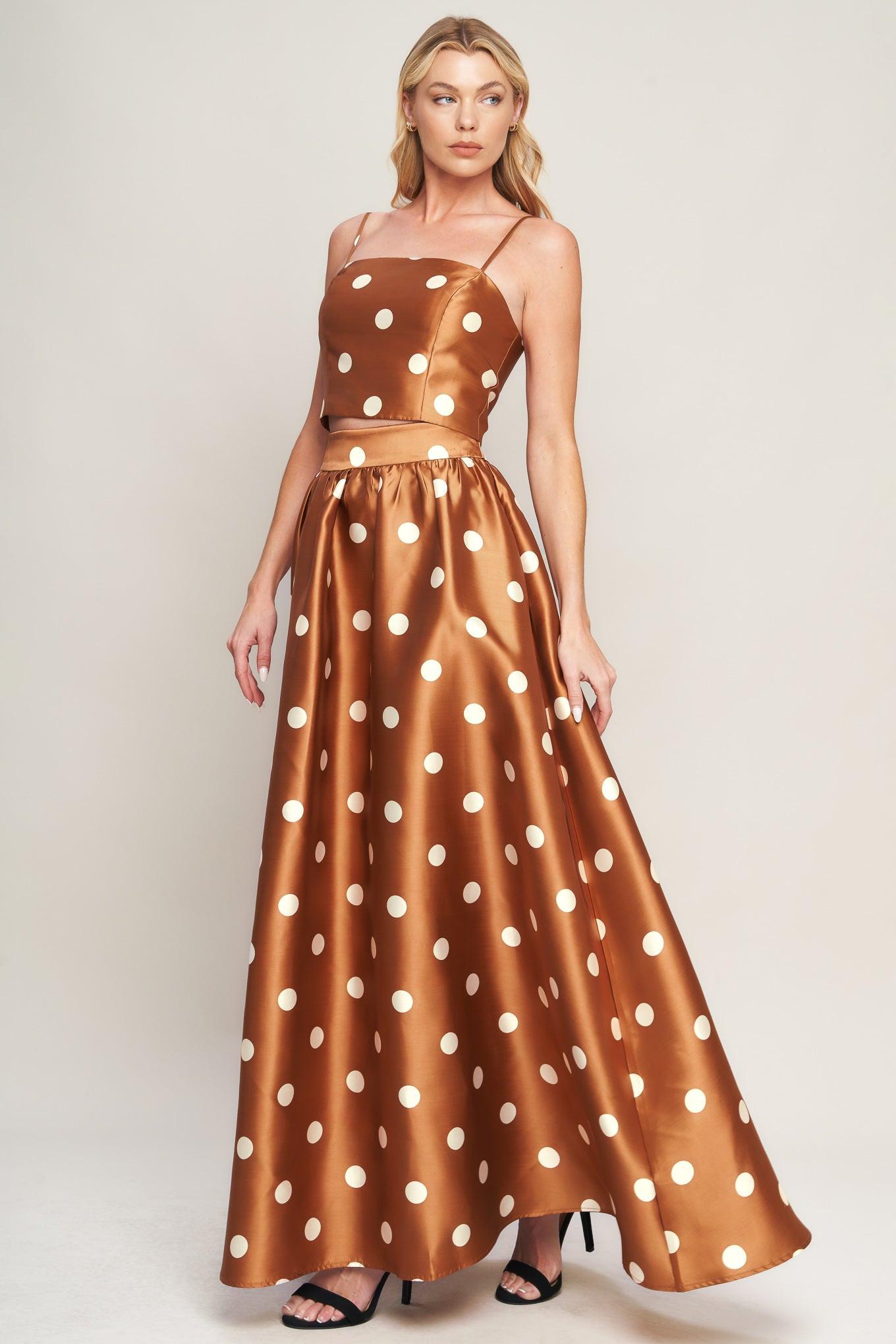 A woman wearing a brown and white polka dot woven maxi skirt with a full, flowing hemline.