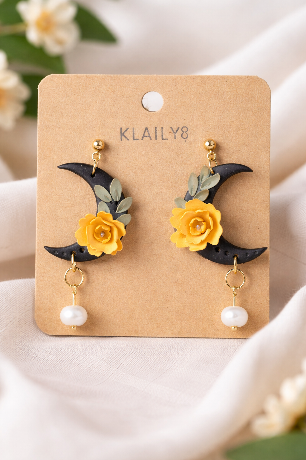 Handmade crescent moon earrings with black and yellow flowers and a freshwater pearl dangle.