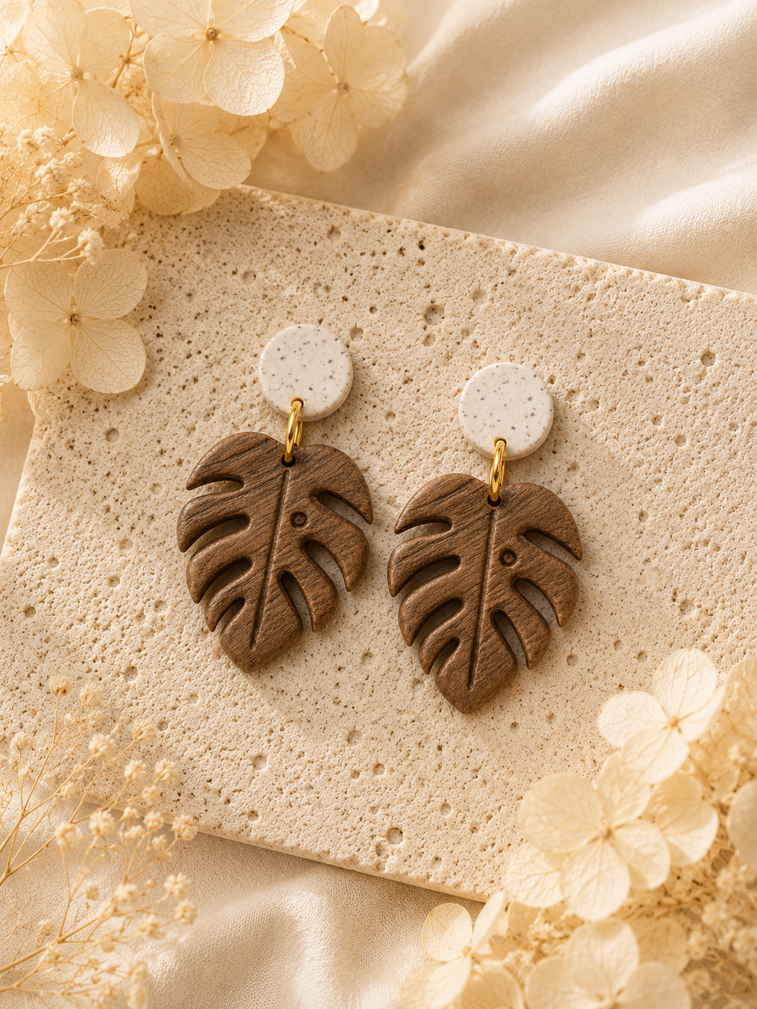 Handcrafted brown wood grain Monstera leaf dangle earrings on a neutral background.