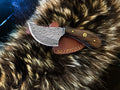 A traditional Damascus steel utility knife with a walnut wood handle and silver blade