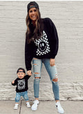 Woman wearing a black and white geometric checkered Mama crew neck sweatshirt