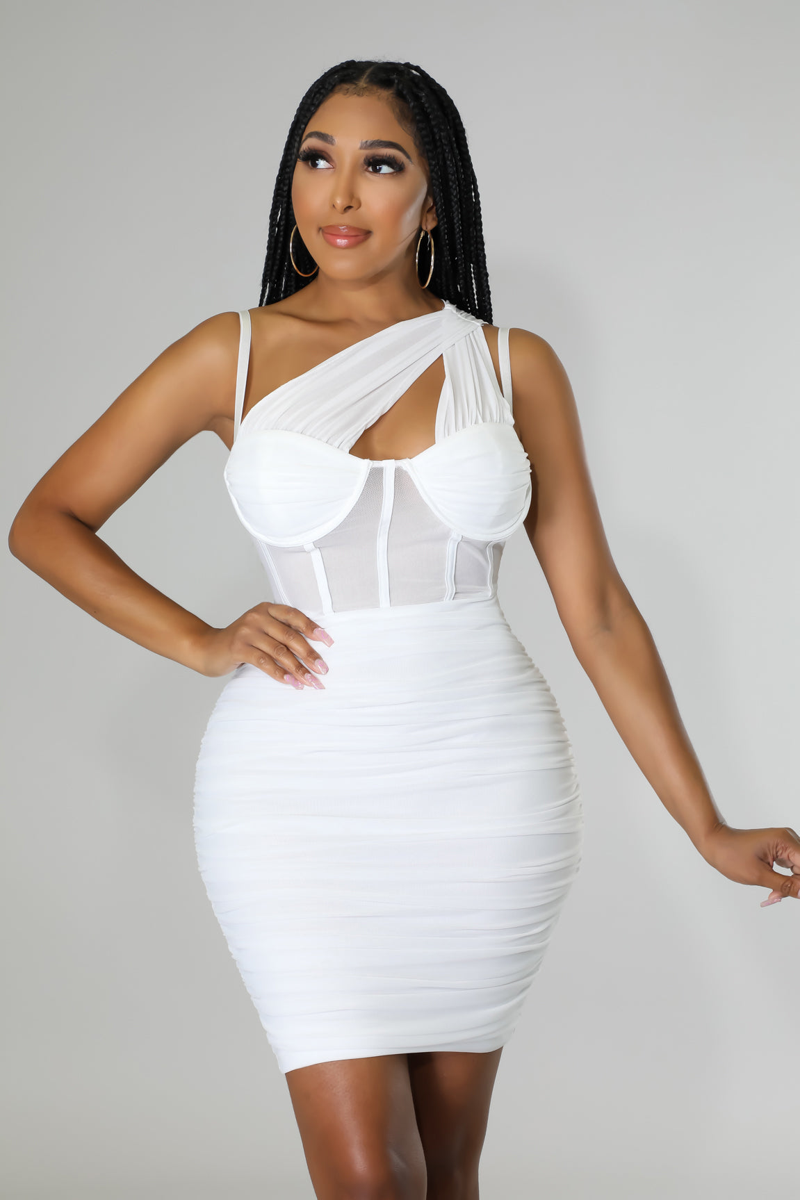 Model wearing a white one-shoulder ruched mini dress with a sheer corset bodice and underwire detailing.