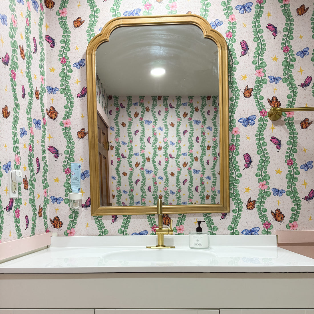 Whimsical bohemian Sylva wallpaper featuring pink and green abstract print on a neutral background.