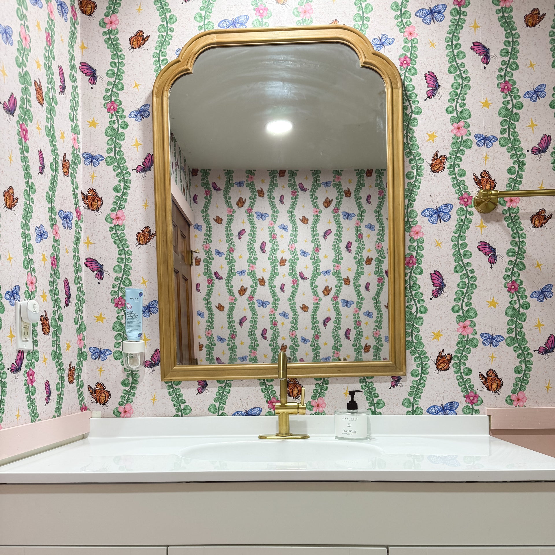Whimsical bohemian Sylva wallpaper featuring pink and green abstract print on a neutral background.