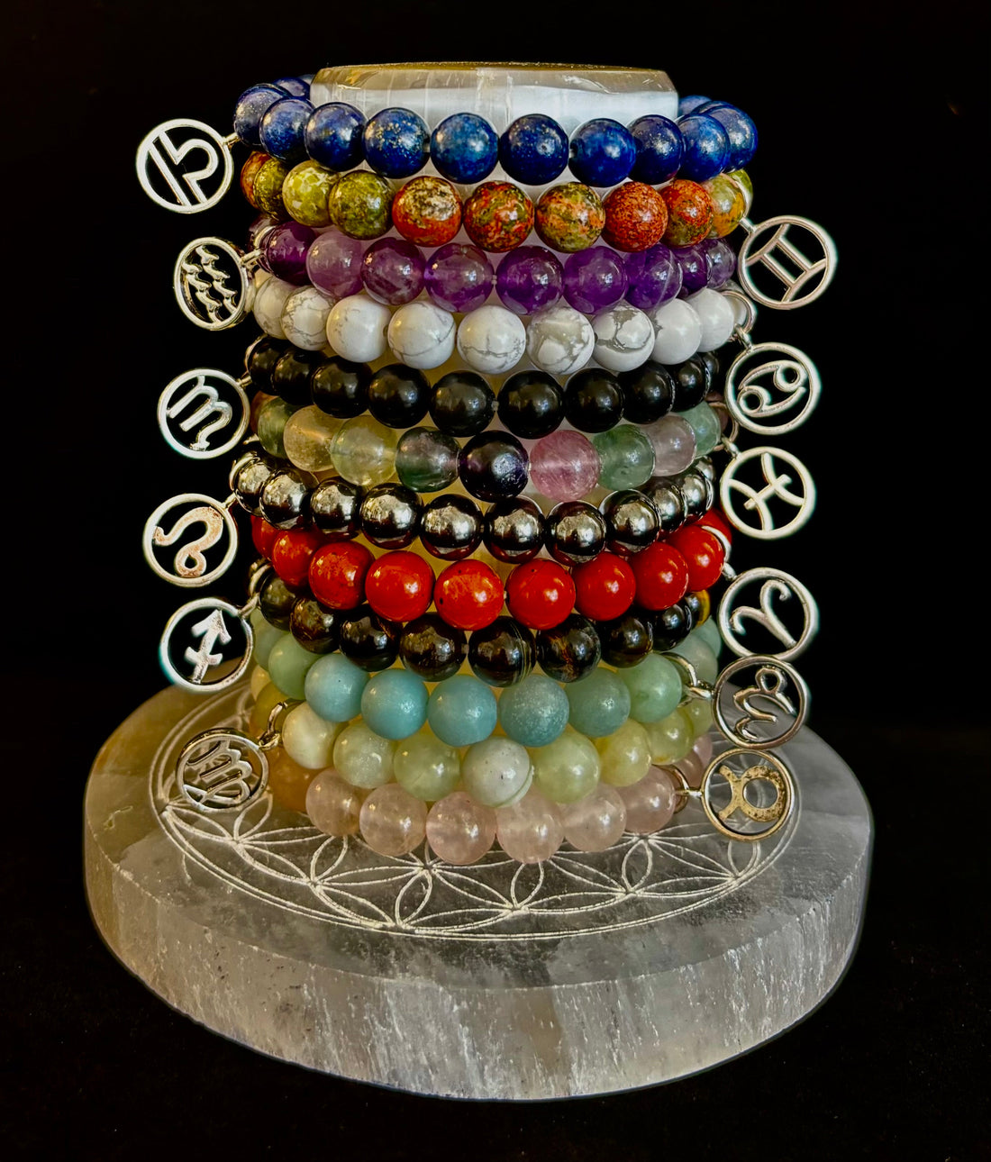Collection of various colored crystal bead bracelets each with a different hanging silver-tone zodiac symbol charm.