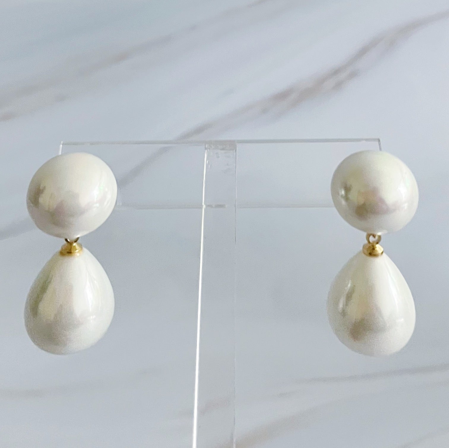 White glass pearl teardrop earrings with 18k gold plated brass findings on an Ellison + Young display card