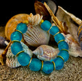 Tidal Serenity Bracelet with teal glass beads, natural shells, and gold brass spacers in a coastal boho style.