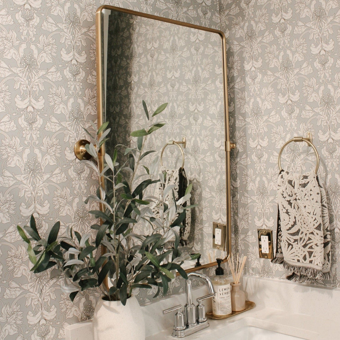 Vera Wallpaper featuring cream botanical floral motifs on a soft sage green background.