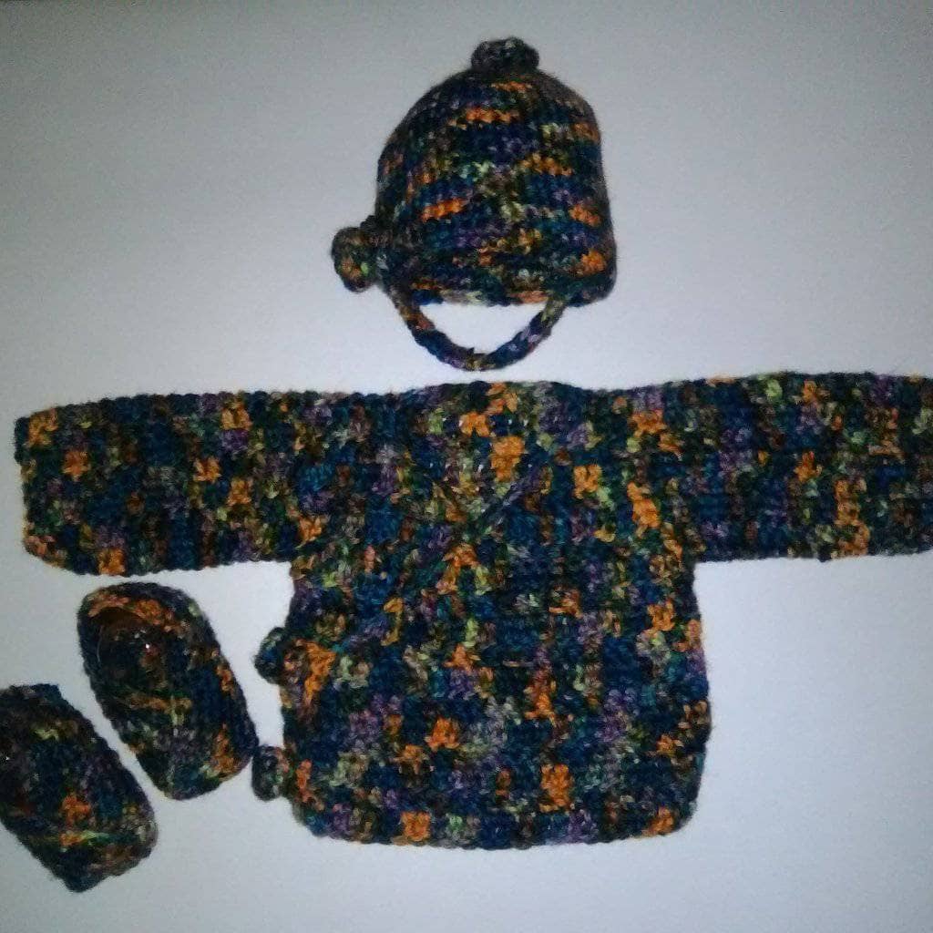 Close up of a handmade crochet newborn duster style cardigan in a cozy knit texture.