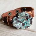 Close up of a genuine ocean agate slab stone mounted on a brown leather strap with metal snap button closures