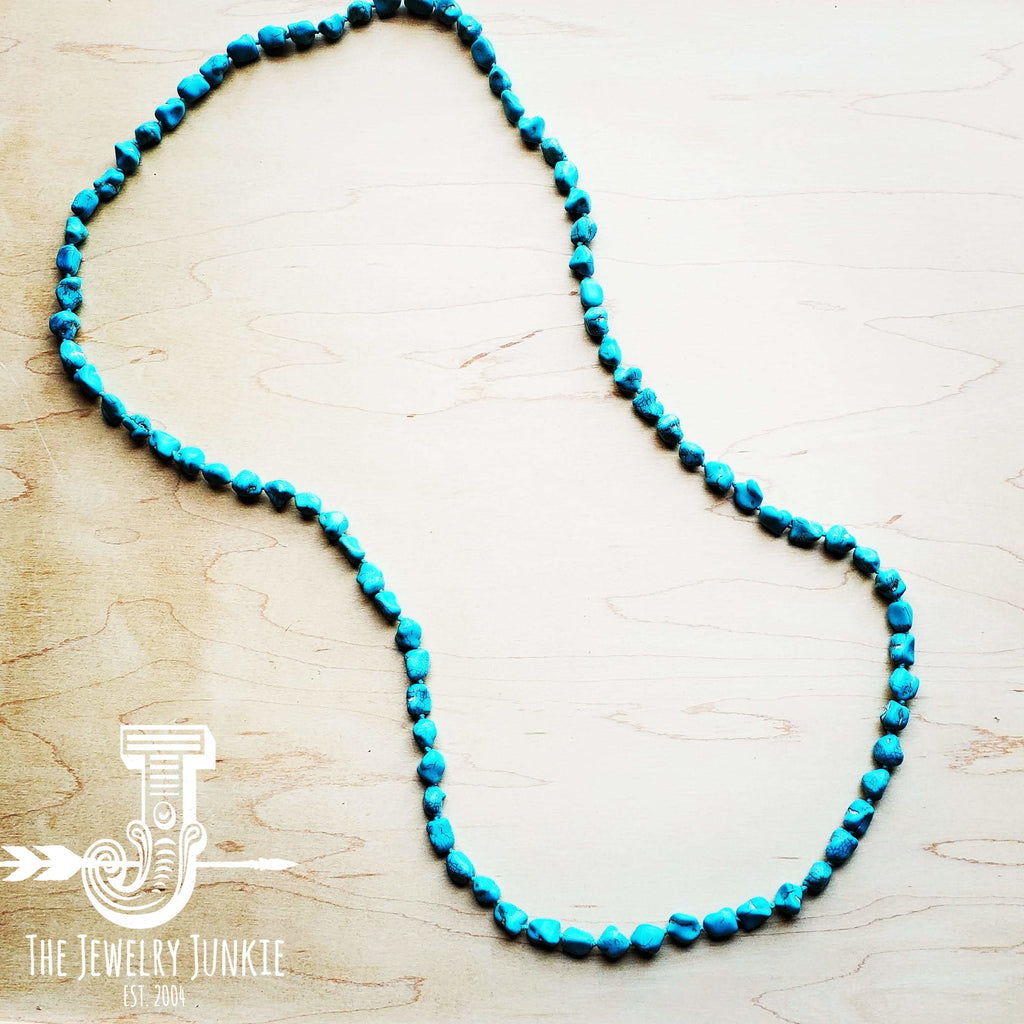Long bohemian style necklace featuring genuine turquoise-colored howlite beads on a wooden background