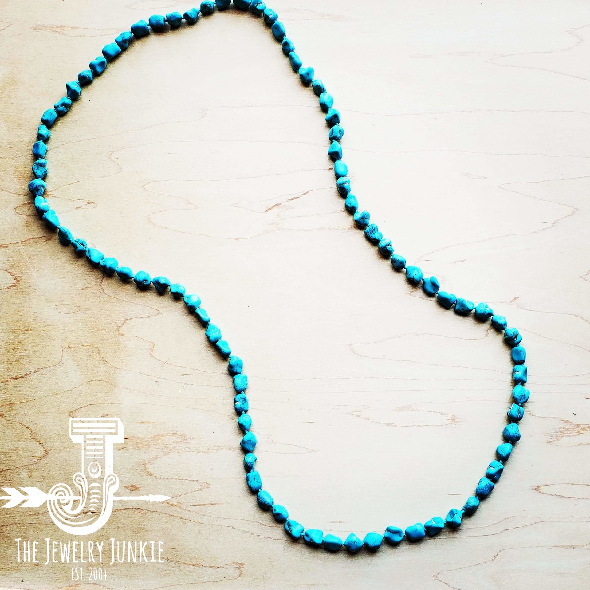 Long bohemian style necklace featuring genuine turquoise-colored howlite beads on a wooden background