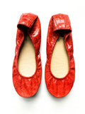 Top-down view of vibrant red textured leather ballet flats featuring a flexible sole design.