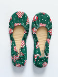 A pair of green holiday-themed ballet flats with a white and red Christmas tree pattern.