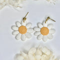 Close-up of golden Retro Daisy Drop earrings featuring a 70s flower aesthetic