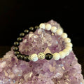 Yin Yang energy bracelet with marbled white and glossy black beads on an amethyst cluster