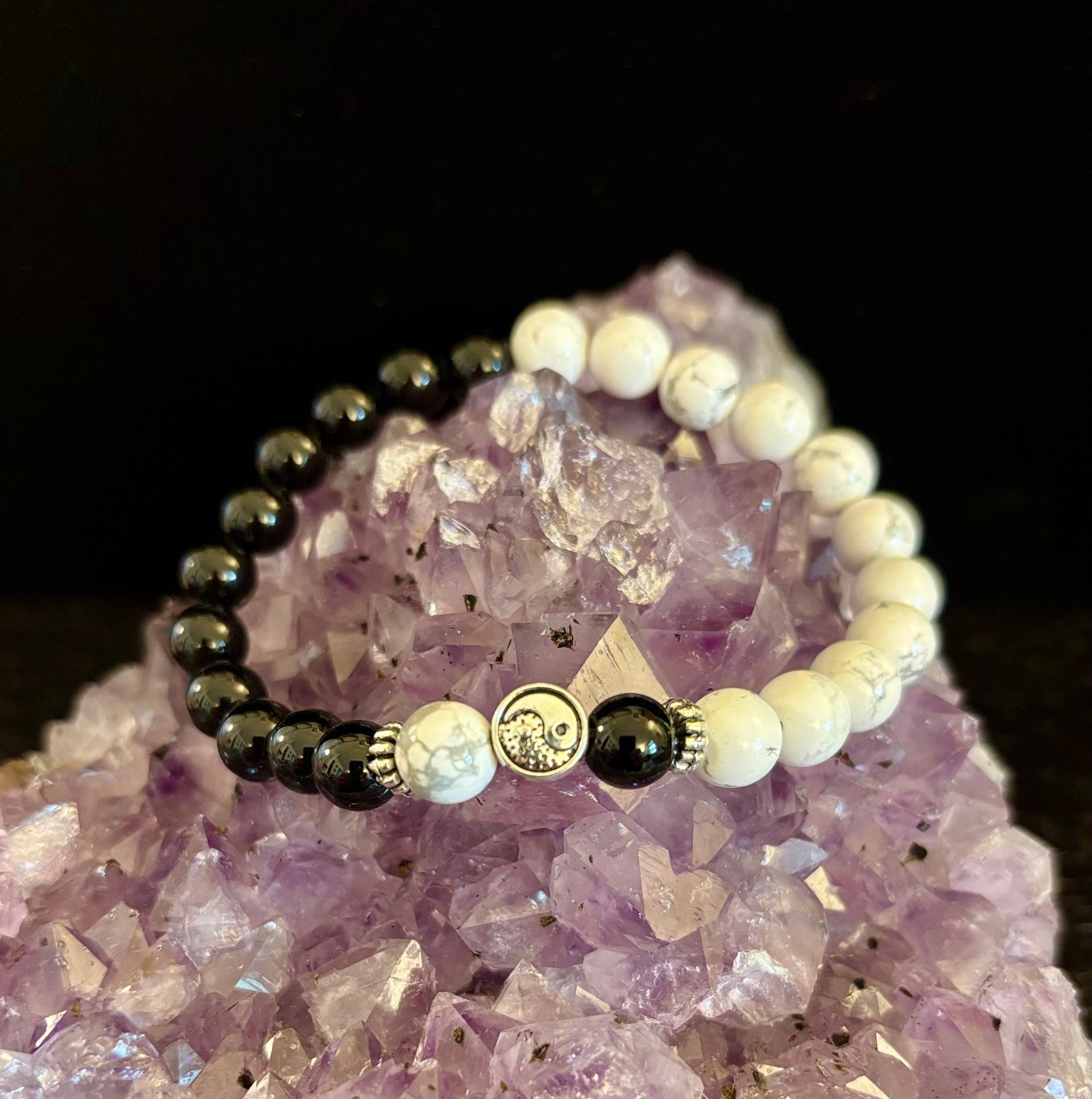 Yin Yang energy bracelet with marbled white and glossy black beads on an amethyst cluster