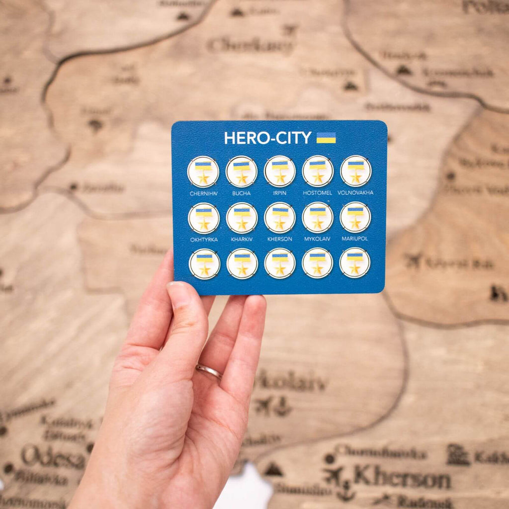 Set of 15 blue, yellow, and gold circular hero-city pins arranged for a wooden map display.