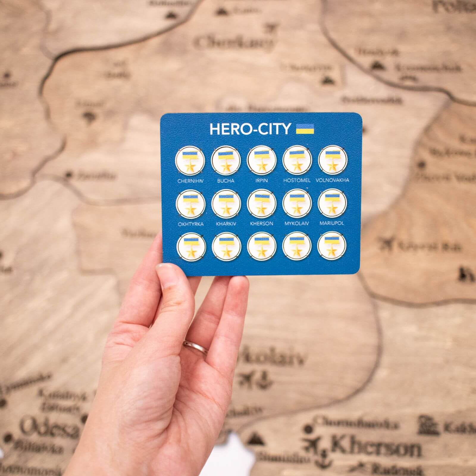 Set of 15 blue, yellow, and gold circular hero-city pins arranged for a wooden map display.