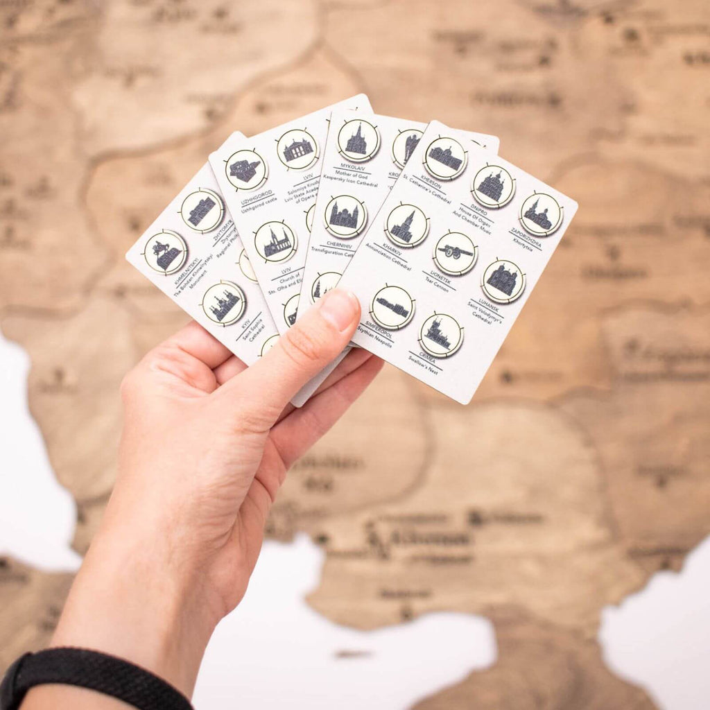 Monochromatic wooden pins featuring Ukrainian landmark icons arranged on a map