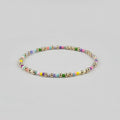 Close up view of a dainty handmade bracelet featuring alternating 14K gold-filled beads and colorful small seed beads on a neutral background.
