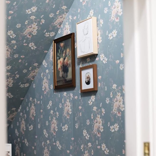 Liesl floral wallpaper with a bohemian aesthetic in dusty blue, white, and pale pink.
